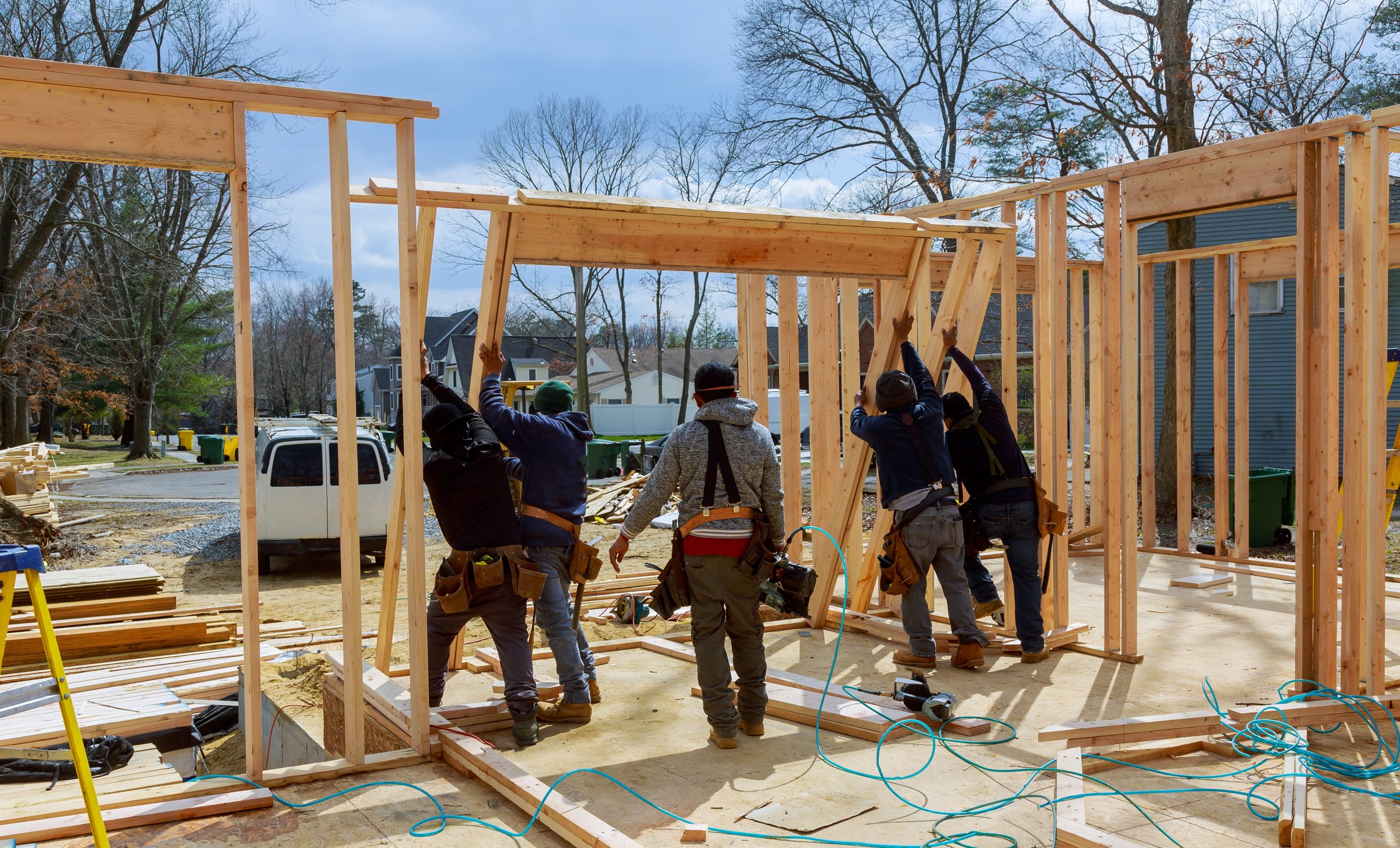 Construction Worker Using nail gun On wood building frame against House Build